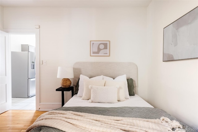 bedroom with fridge with ice dispenser and light wood-style flooring