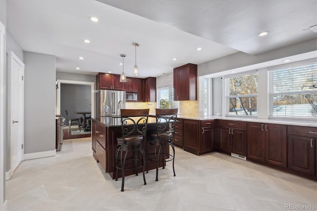 kitchen with hanging light fixtures, a kitchen breakfast bar, a kitchen island, stainless steel appliances, and backsplash