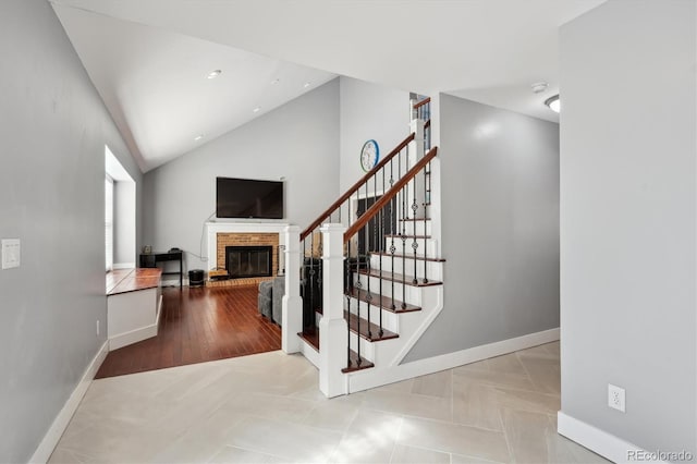 stairs with lofted ceiling and a fireplace