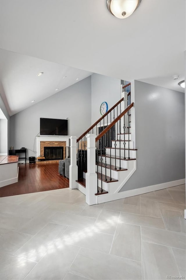 stairway with lofted ceiling and a brick fireplace