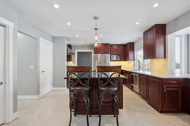 kitchen with sink, hanging light fixtures, a kitchen island, stainless steel appliances, and backsplash