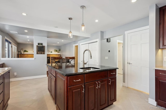 kitchen featuring sink, decorative light fixtures, and an island with sink