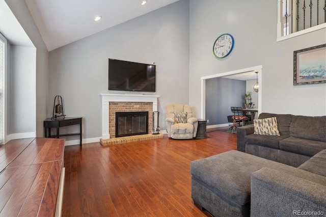 living room with a fireplace, high vaulted ceiling, and wood-type flooring