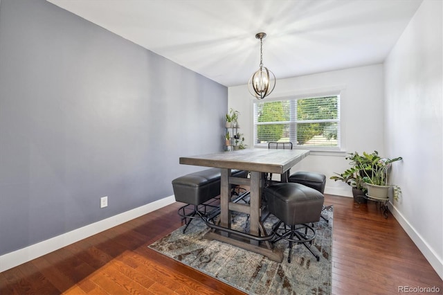 dining area with dark wood-type flooring and a notable chandelier