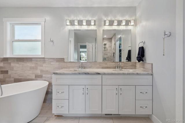 bathroom with plenty of natural light, independent shower and bath, vanity, and tile walls