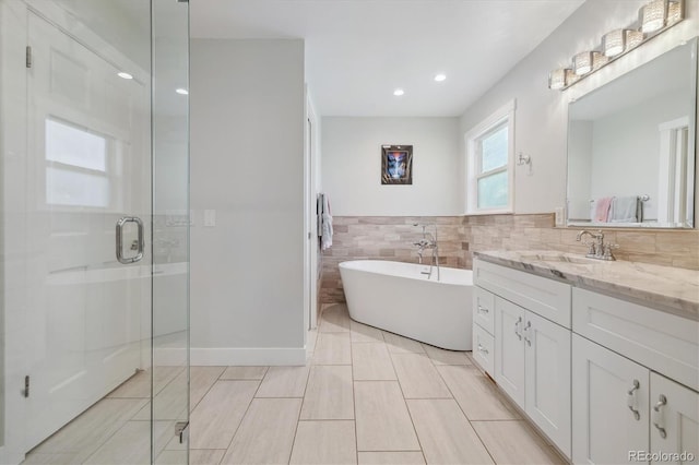 bathroom with vanity, shower with separate bathtub, and tile walls