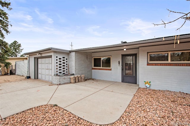 view of front of property with a garage, concrete driveway, and brick siding