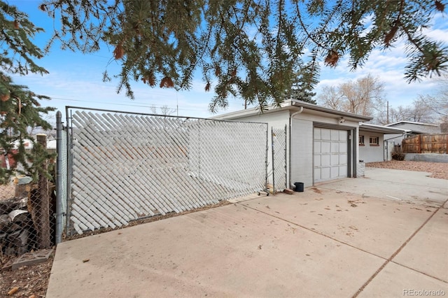 garage with driveway, fence, and a gate