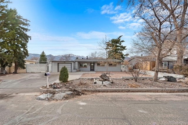 ranch-style house with driveway, an attached garage, fence, and stucco siding