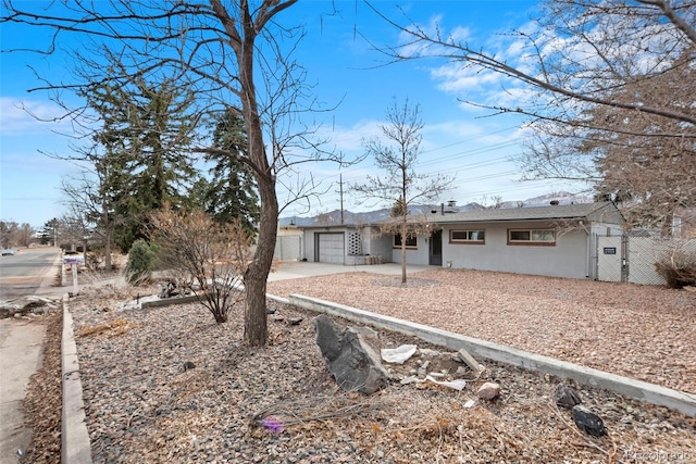 ranch-style house featuring driveway, an attached garage, fence, and a gate