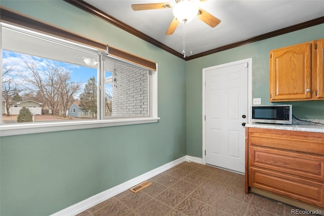 interior space with baseboards, ceiling fan, visible vents, and crown molding