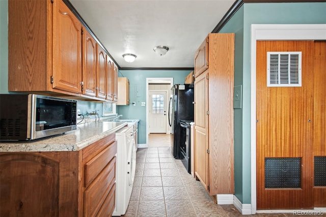 kitchen featuring brown cabinets, ornamental molding, black appliances, washer / dryer, and baseboards