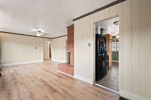 spare room featuring ornamental molding, light wood-type flooring, a fireplace, and a ceiling fan