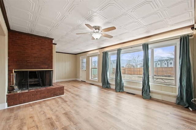 unfurnished living room with an ornate ceiling, a fireplace, visible vents, light wood-style flooring, and baseboards