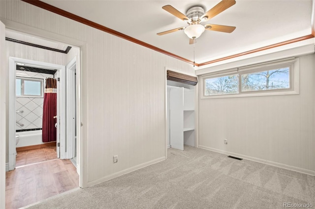 unfurnished bedroom featuring connected bathroom, carpet floors, visible vents, baseboards, and ornamental molding