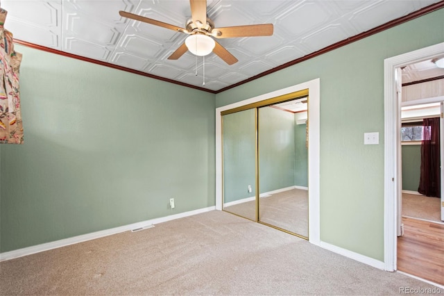 unfurnished bedroom with an ornate ceiling, crown molding, baseboards, and a closet