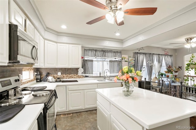 20292 E 47th Ave, Denver, CO 80249 - kitchen with a center island, electric stove, a ceiling fan, stainless steel microwave, and backsplash