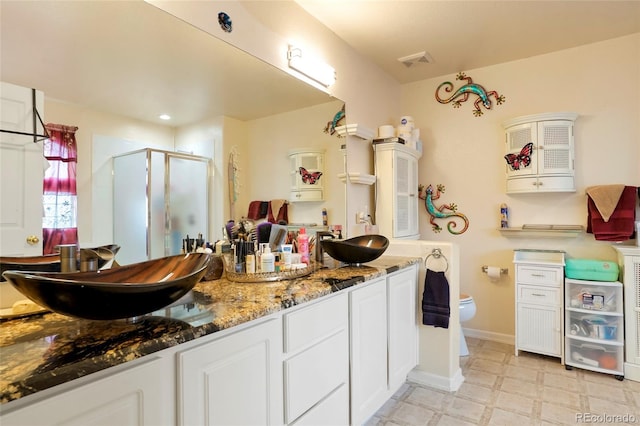 20292 E 47th Ave, Denver, CO 80249 - bathroom with a sink, double vanity, toilet, visible vents, and a stall shower