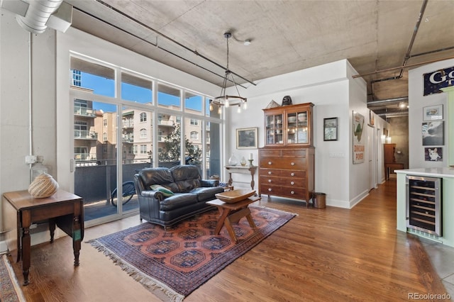 living room featuring a notable chandelier, a towering ceiling, beverage cooler, and dark hardwood / wood-style flooring