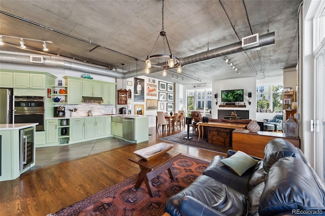 living room with dark hardwood / wood-style flooring, track lighting, and beverage cooler