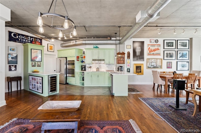 kitchen featuring stainless steel appliances, a center island, decorative light fixtures, and green cabinetry