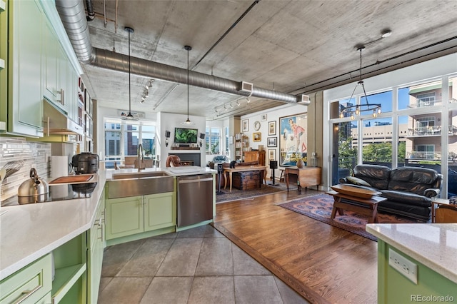 kitchen featuring stainless steel dishwasher, open floor plan, a sink, and green cabinets