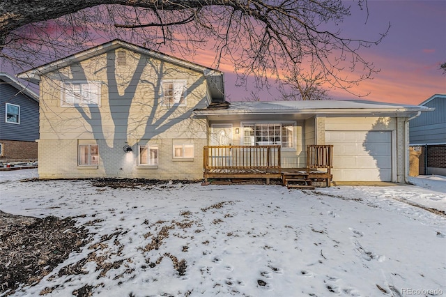 snow covered property with a garage and a porch