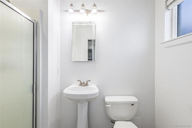 bathroom with a shower with shower door and toilet