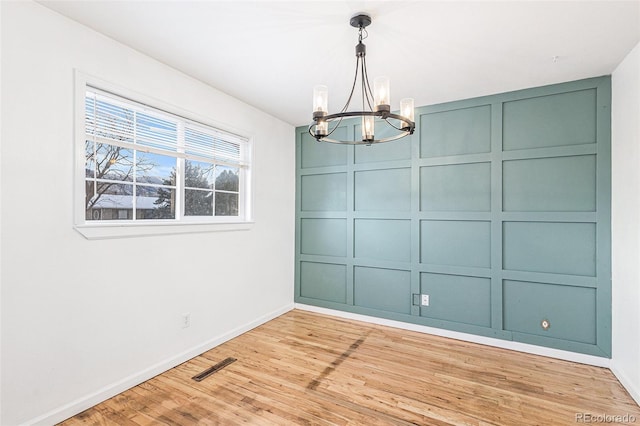 unfurnished dining area featuring a chandelier and light hardwood / wood-style flooring