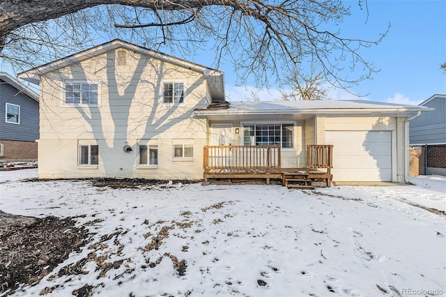 snow covered back of property with a garage and covered porch