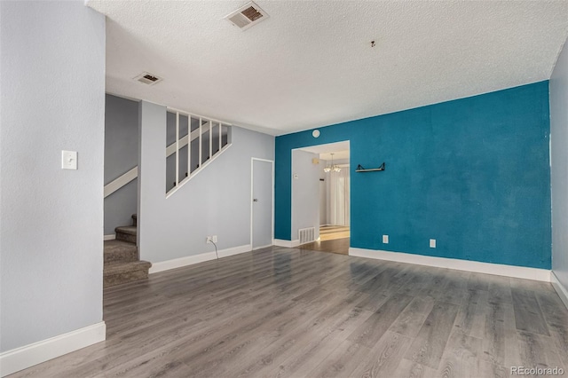 empty room featuring visible vents, wood finished floors, and stairs