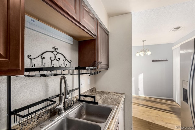 kitchen with visible vents, a chandelier, stainless steel refrigerator with ice dispenser, wood finished floors, and a sink