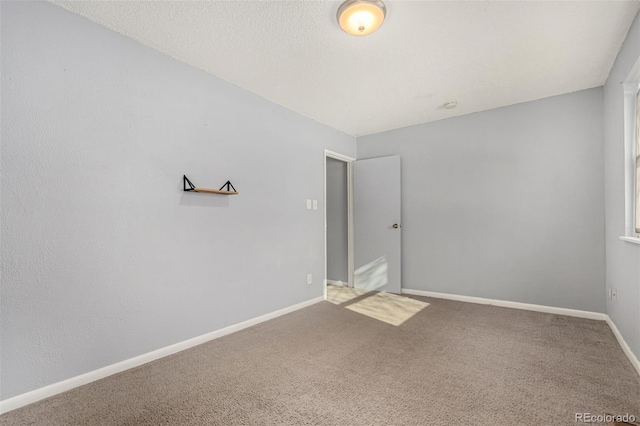 carpeted spare room with baseboards and a textured ceiling