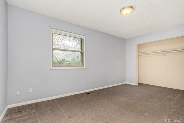 unfurnished bedroom featuring visible vents, a textured ceiling, a closet, carpet floors, and baseboards