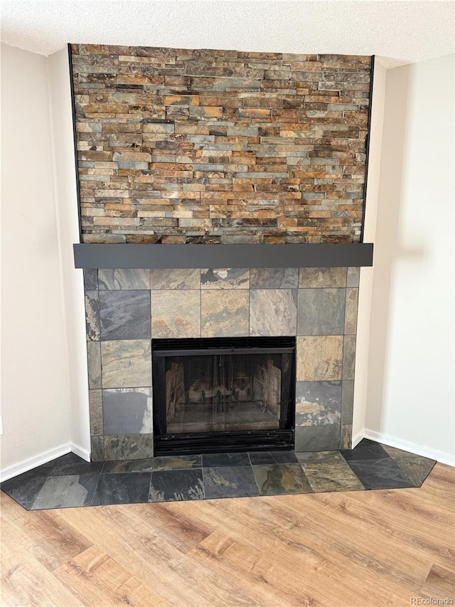 details with wood finished floors, a fireplace, baseboards, and a textured ceiling