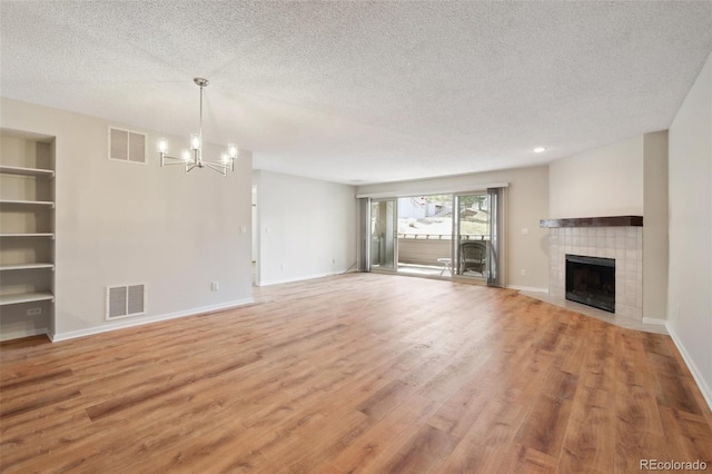 unfurnished living room with a textured ceiling, a notable chandelier, and visible vents