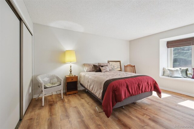 bedroom featuring a closet, a textured ceiling, wood finished floors, and baseboards