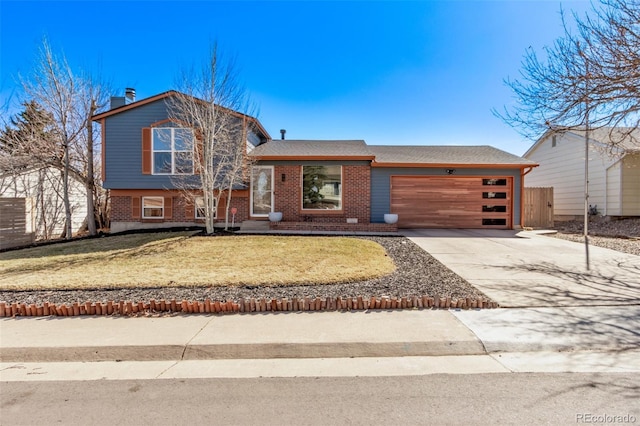 tri-level home featuring concrete driveway, brick siding, an attached garage, and a front lawn