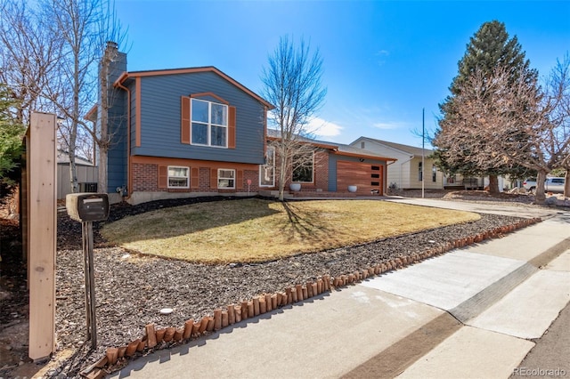 split level home with concrete driveway, a front lawn, a chimney, and brick siding