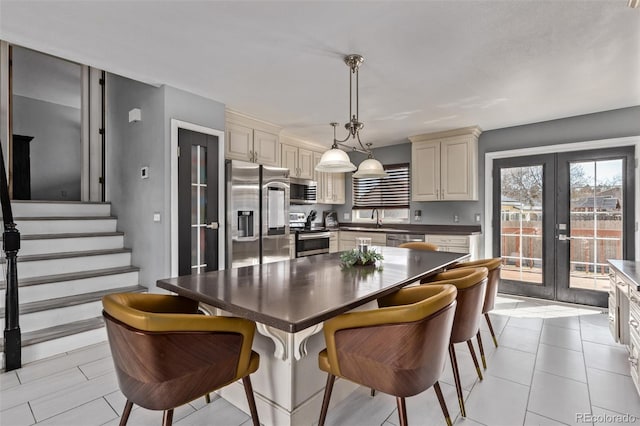 kitchen featuring french doors, a breakfast bar area, stainless steel appliances, dark countertops, and cream cabinets