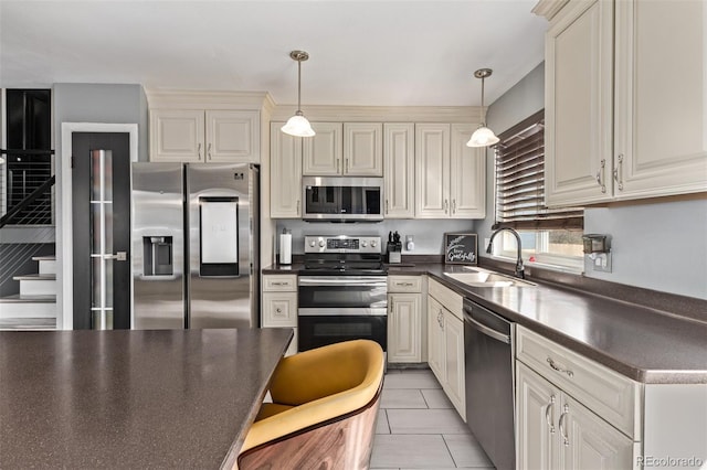 kitchen with dark countertops, hanging light fixtures, appliances with stainless steel finishes, light tile patterned flooring, and a sink