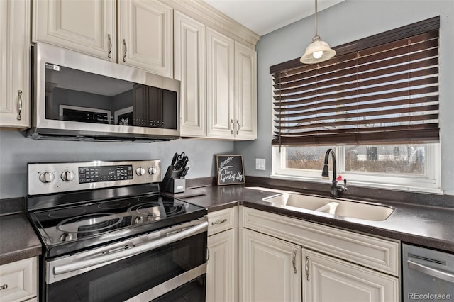 kitchen with dark countertops, stainless steel appliances, a sink, and decorative light fixtures