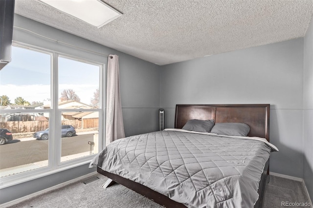 bedroom with a textured ceiling, carpet floors, visible vents, and baseboards