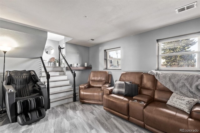 living area featuring stairs, visible vents, and a textured ceiling