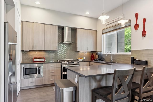 2898 W 22nd Ave, Denver, CO 80211 - kitchen featuring wall chimney range hood, stainless steel appliances, a sink, a peninsula, and a breakfast bar area