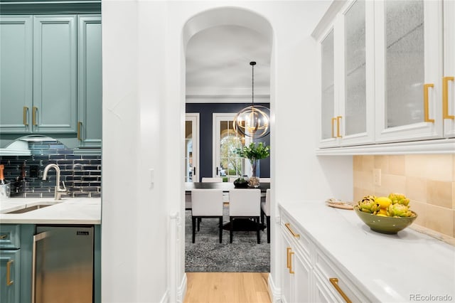 1164 S High St, Denver, CO 80210 - kitchen featuring light countertops, light wood-style flooring, backsplash, arched walkways, and crown molding