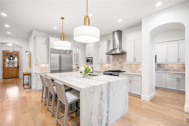 1164 S High St, Denver, CO 80210 - kitchen featuring wall chimney exhaust hood, built in appliances, arched walkways, tasteful backsplash, and recessed lighting