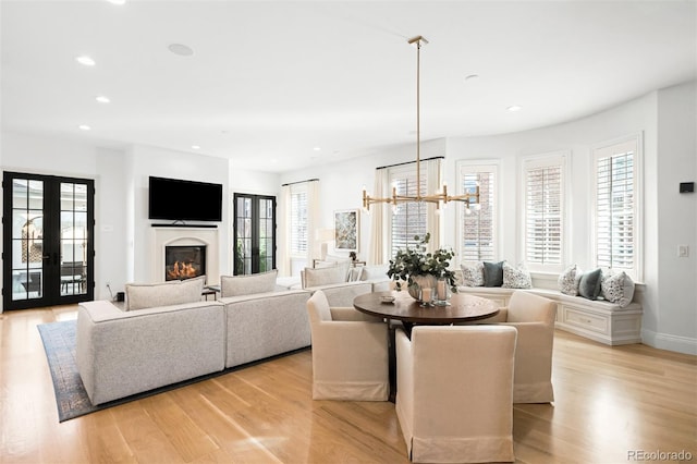 1164 S High St, Denver, CO 80210 - dining space featuring light wood-style floors, french doors, recessed lighting, a glass covered fireplace, and a chandelier