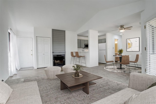 living room featuring ceiling fan, lofted ceiling, a healthy amount of sunlight, and a large fireplace