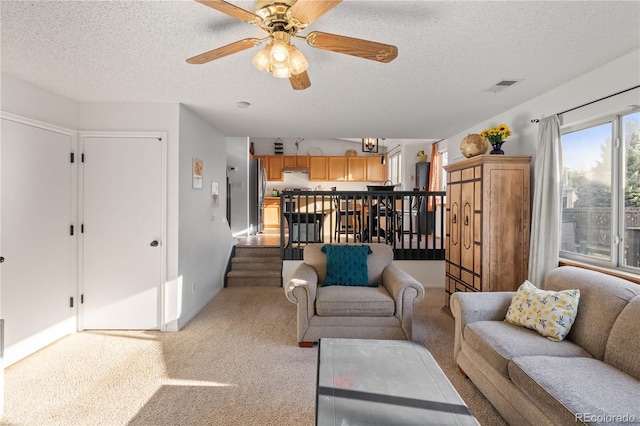 4363 E Andover Ave, Castle Rock, CO 80104 - living room featuring a textured ceiling, light colored carpet, ceiling fan, and stairway